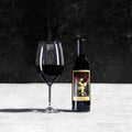 Wine bottle and glass on a textured surface with a dark background