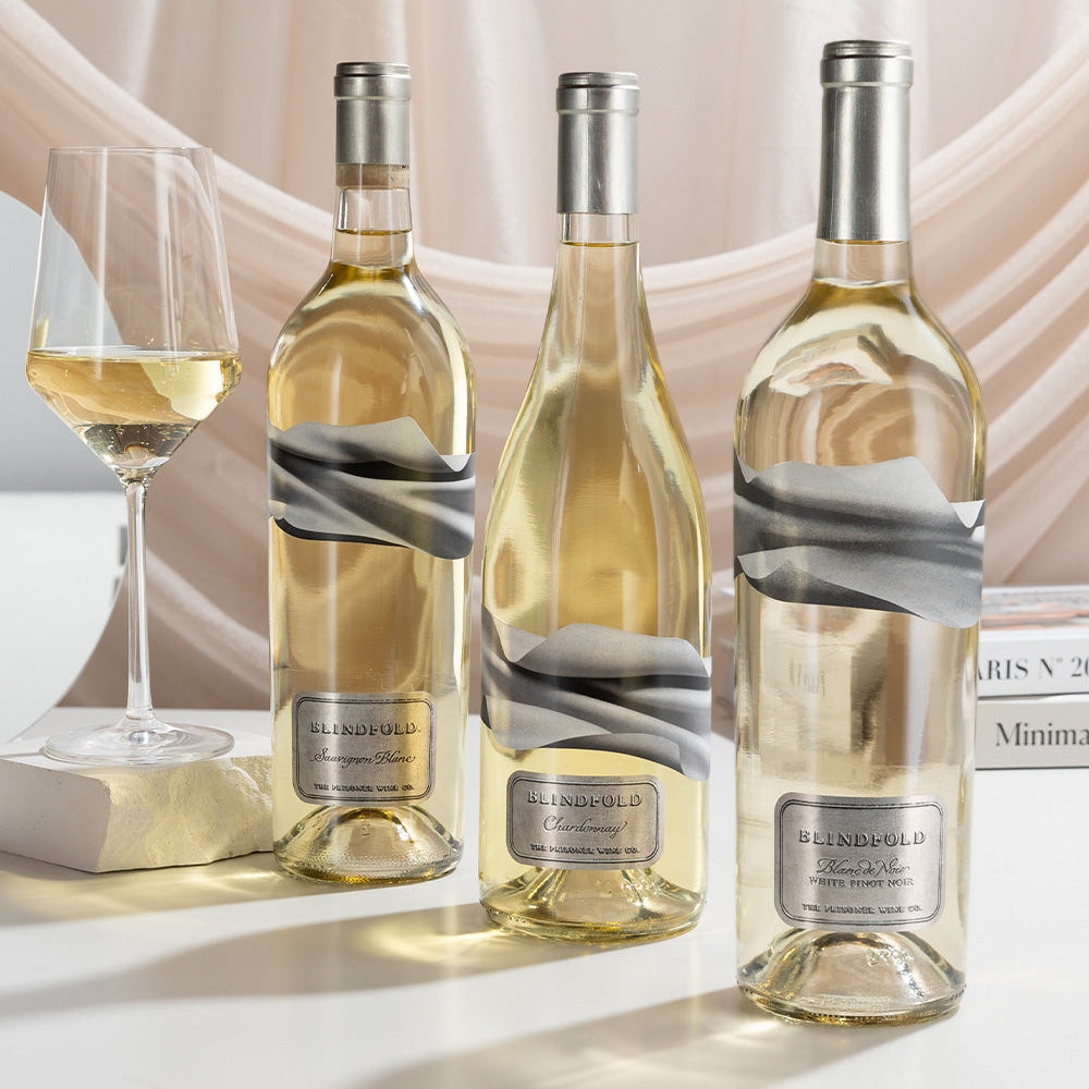 Three bottles of Blindfold wines with a glass on a light background