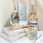 Bottle of white wine on a table with decorative items including a mirror, books, and a vase.