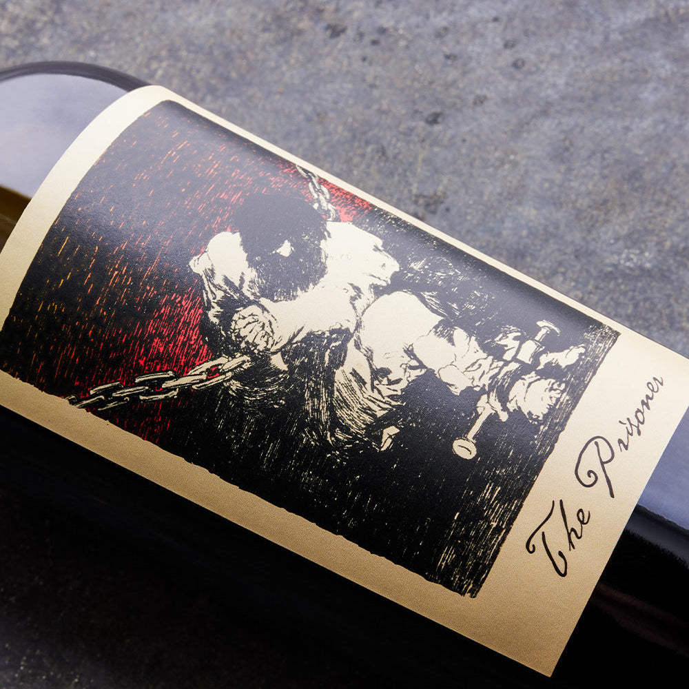 Wine bottle label with artistic depiction of a person and text 'The Prisoner' on a dark surface.