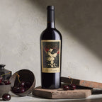 A bottle of The Prisoner Red Blend on a stone surface with cherries
