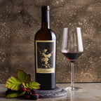 A bottle of The Prisoner Red Blend and glass of red wine on a textured surface