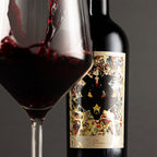 A bottle of The Prisoner Winemaker Series with decorative label next to a filled wine glass on a dark background