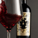 Wine bottle with decorative label next to a glass of red wine.