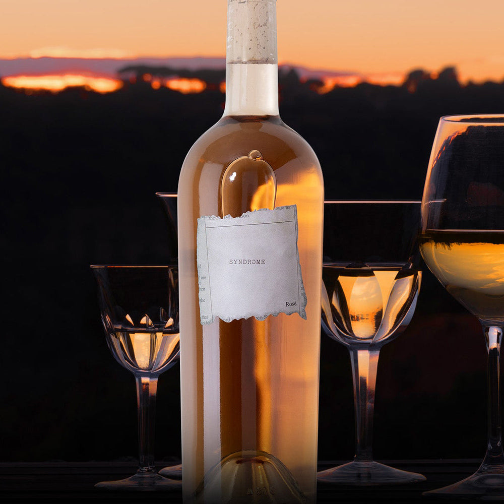 Wine bottle with glasses against a sunset backdrop