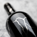 Bottle of Grenache Syrah Mourvedre on its side on gray background