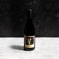 A bottle of the Prisoner Pinot Noir against a gray background with a sharp shadow
