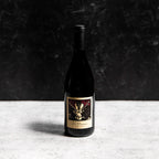 A bottle of the Prisoner Pinot Noir against a gray background with a sharp shadow