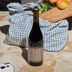 Unshackled Pinot Noir bottle on a checkered blanket with flowers in the background