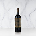 A bottle of Unshackled Cabernet Sauvignon with a gold and black label on a marble background