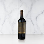 A bottle of Unshackled Cabernet Sauvignon with a gold and black label on a marble background