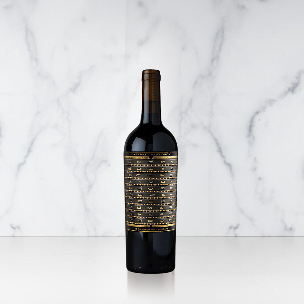 A bottle of Unshackled Cabernet Sauvignon with a gold and black label on a marble background