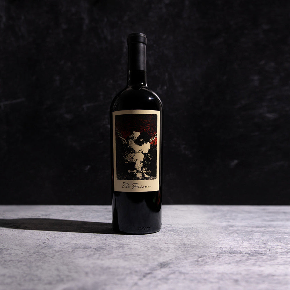 A bottle of The Prisoner Red Blend with a label on a dark background