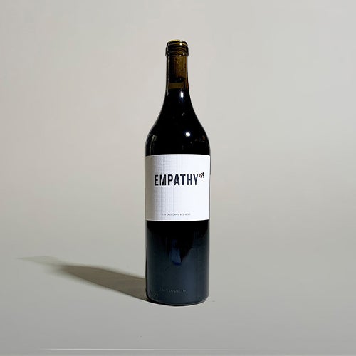 A bottle of 2019 Empathy Red Wine, front label facing forward, on a light gray background with a faint shadow being cast to the left side.