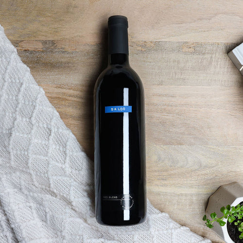 Black wine bottle with a blue label on a wooden surface